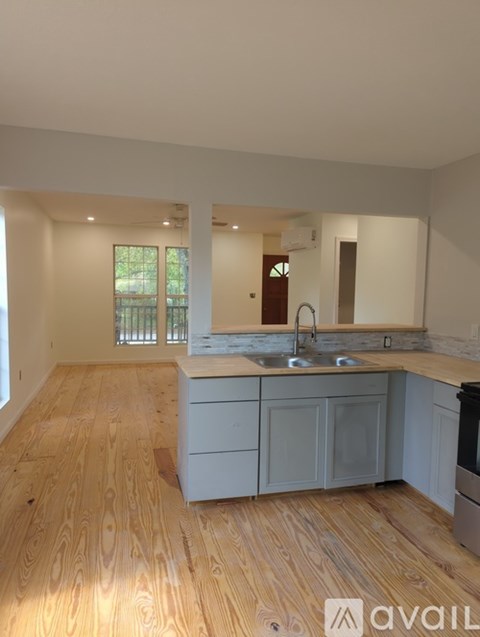 A kitchen with wooden floors and a countertop with a sink and a dishwasher.