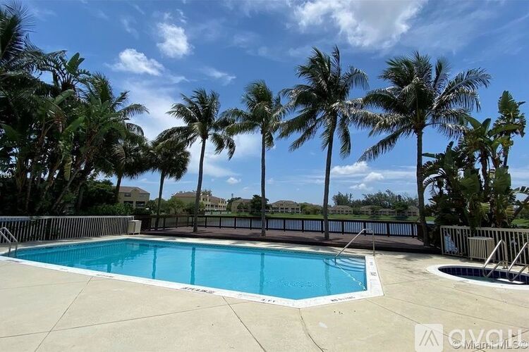 A pool surrounded by palm trees under a blue sky.