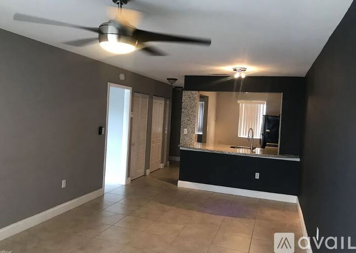 A spacious room with a ceiling fan and a bathroom with a mirror and sink.