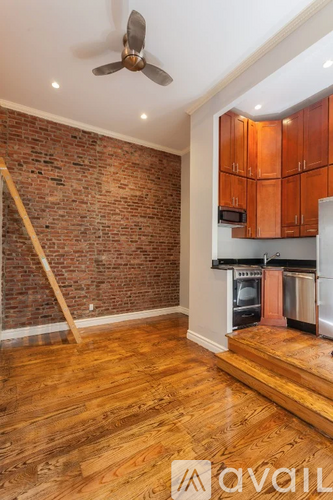 A kitchen with wooden floors and a brick wall.