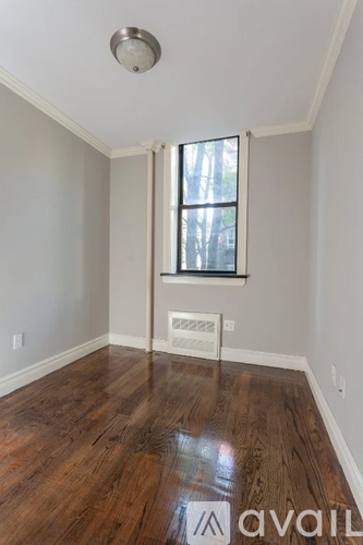 A room with wooden floors and a window with a white frame.