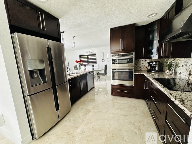 A kitchen with a stainless steel refrigerator and dark brown cabinets.