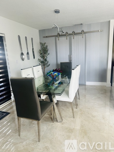A modern dining room with a glass table and chairs.