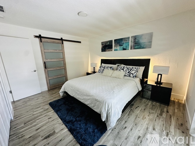 A bedroom with a bed, nightstand, and a door with a window.