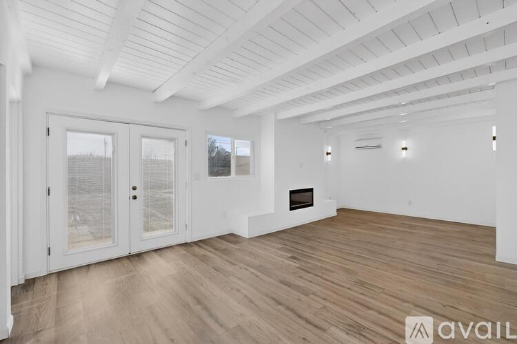 A spacious room with wooden flooring and white walls.