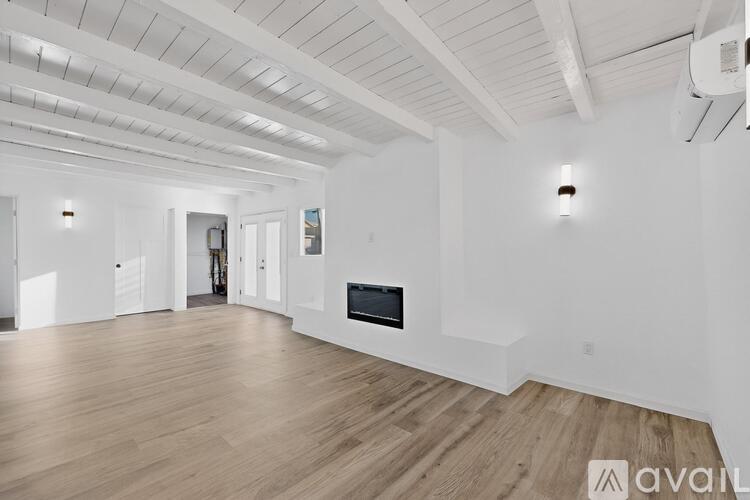 A spacious living room with wooden floors and white walls.