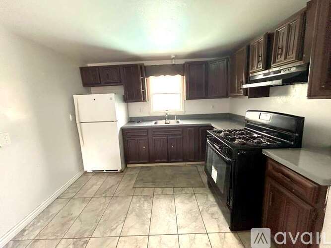 A kitchen with a black stove top oven and a white refrigerator.