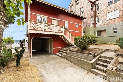 A red building with a balcony and stairs leading to a door.
