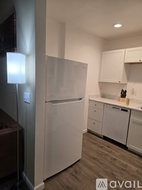 A white refrigerator in a kitchen with white cabinets.