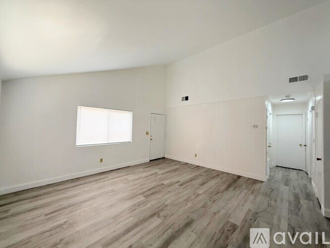 A spacious room with wooden flooring and white walls.