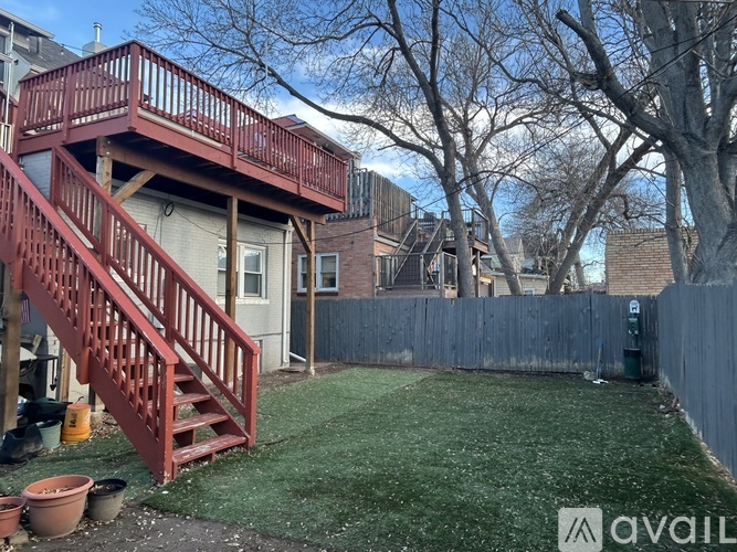 A backyard with a red staircase and a green lawn.