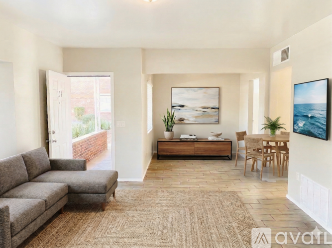 A living room with a grey sofa, a wooden bench, and a painting on the wall.