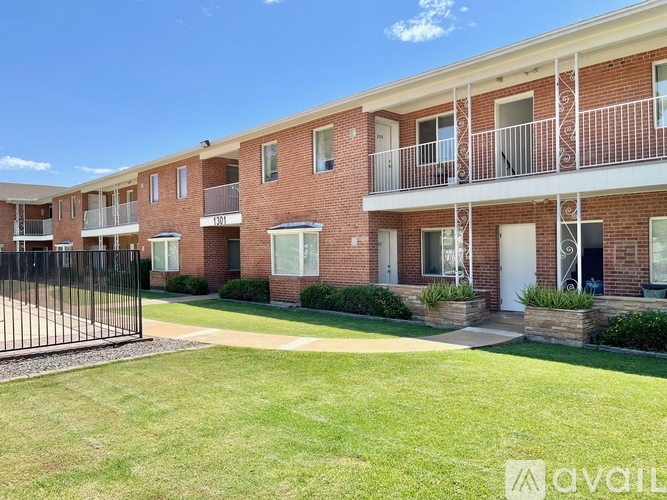A row of red brick apartment buildings with balconies and a black gate in front.