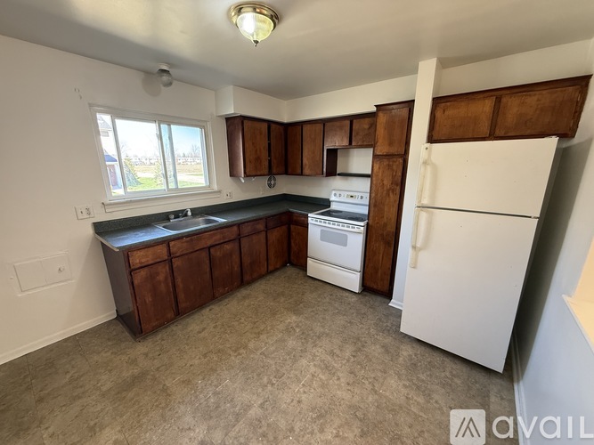 A kitchen with white appliances and brown cabinets.