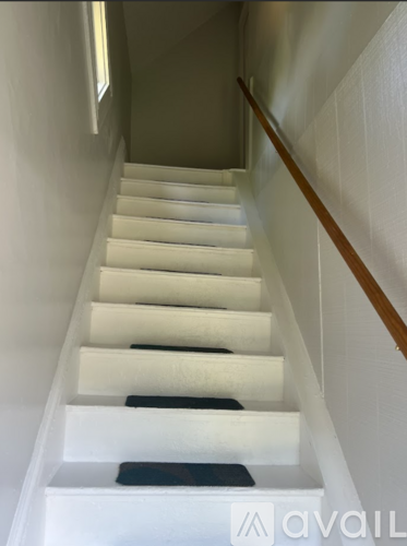 A staircase with white steps and a wooden handrail.