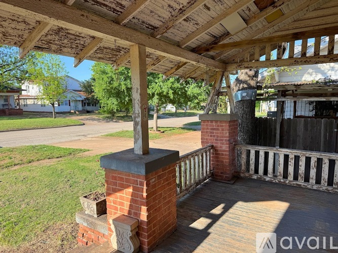 A wooden porch with a brick pillar and a railing.