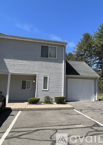 A two-story house with a garage and a car parked in front.