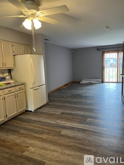 A kitchen with a white fridge and wooden floors.