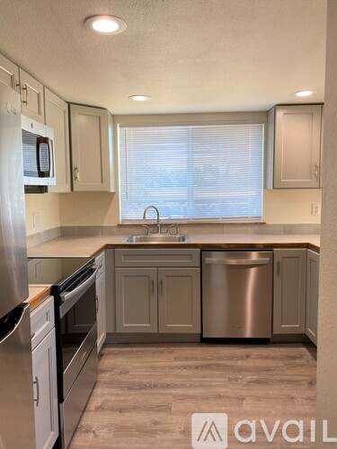 A kitchen with a sink, dishwasher, and refrigerator.