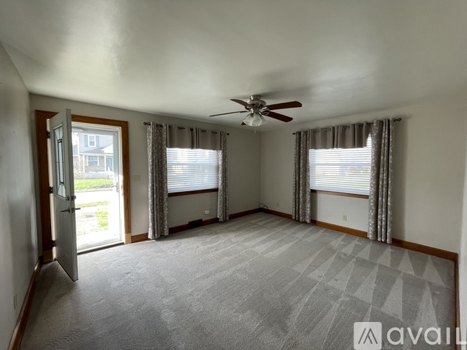 A spacious room with a ceiling fan and sliding glass doors.