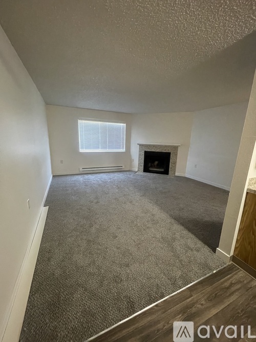 A room with a carpeted floor and a fireplace.