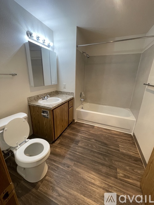 A bathroom with a toilet, sink, mirror, and bathtub.