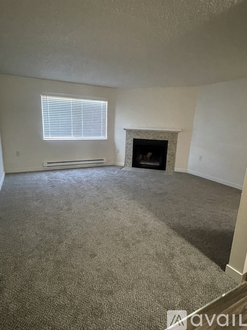 A living room with a fireplace and a window with blinds.
