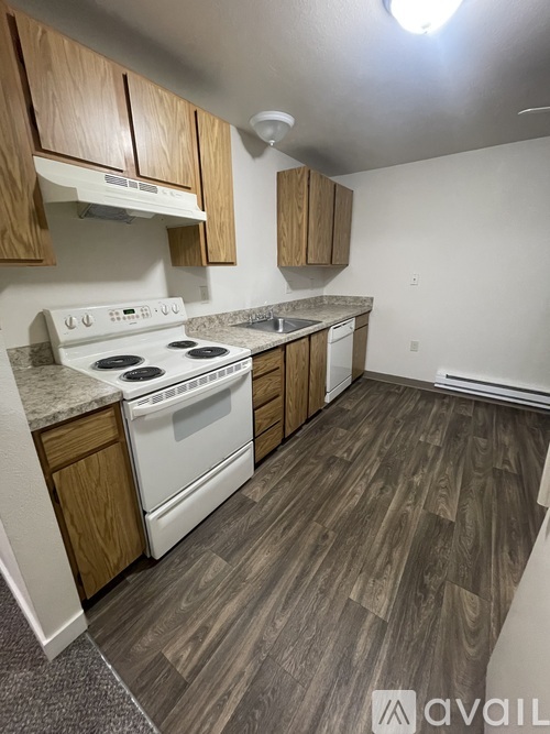 A kitchen with a white stove top oven and wooden cabinets.