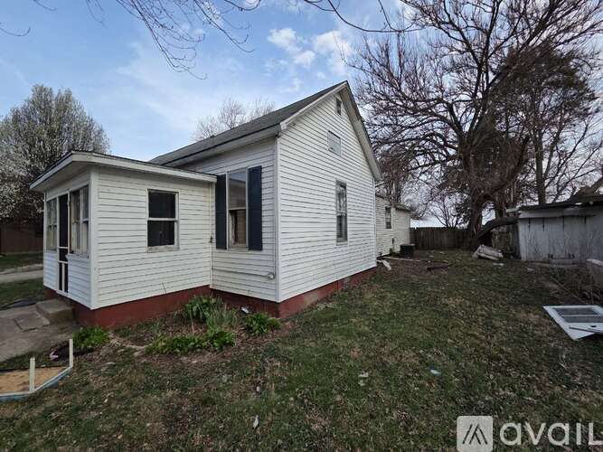 A small white house with a red brick foundation and a black door.