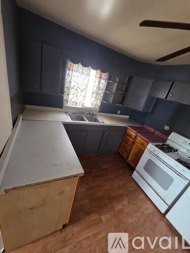 A kitchen with a white stove top oven and a window with curtains.