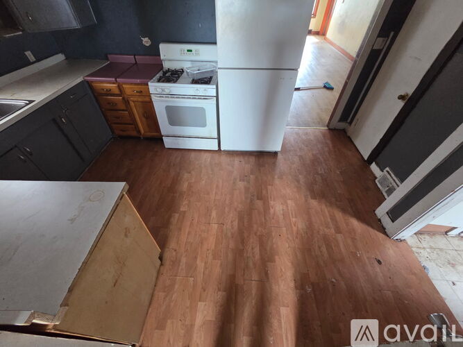 A kitchen with a white refrigerator and wooden floors.