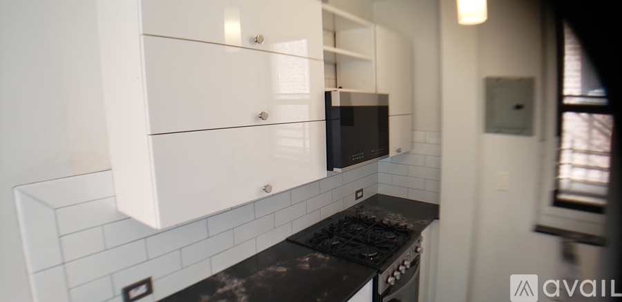 A kitchen with white cabinets and a black counter top.