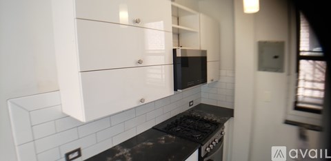 A kitchen with white cabinets and a black counter top.