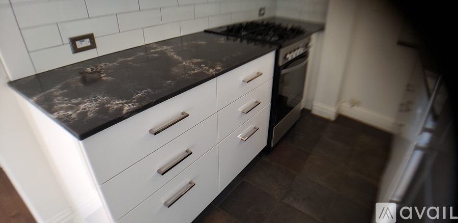 A kitchen with a black granite counter top and white cabinets.
