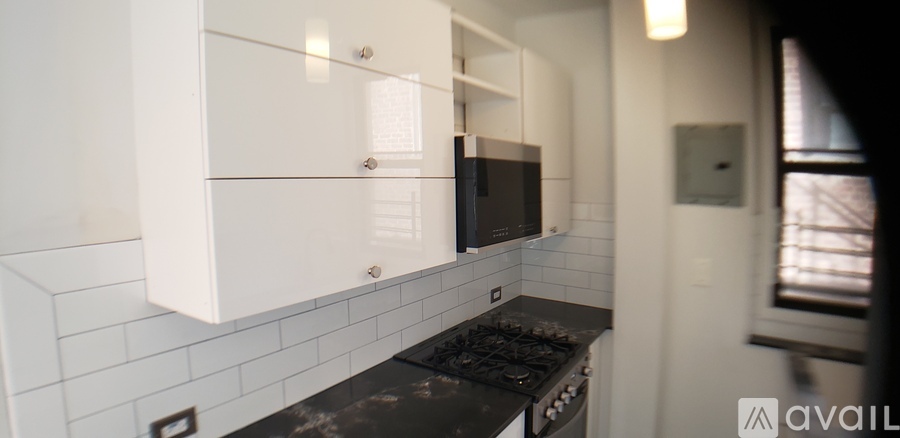 A kitchen with white cabinets and a black countertop.