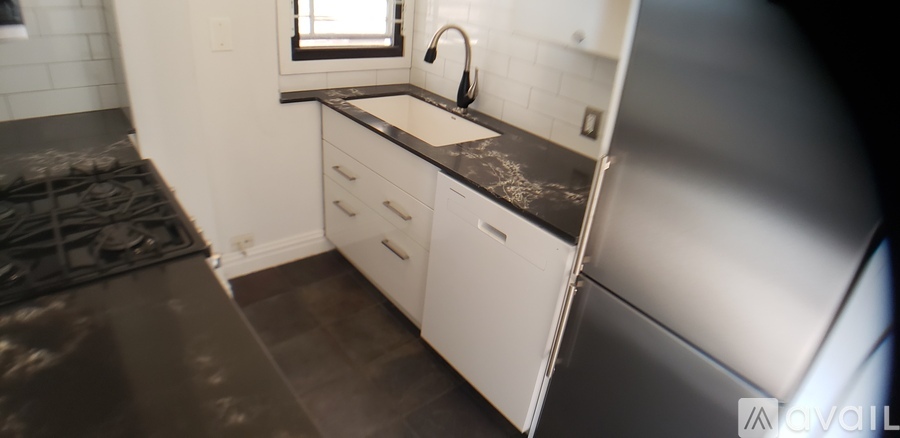 A kitchen with white cabinets and a black countertop.