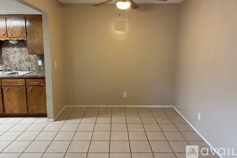 A kitchen with wooden cabinets and a tiled floor.