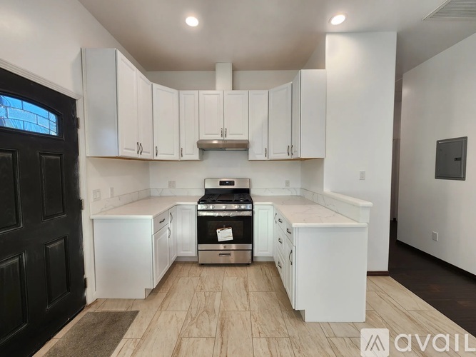 A kitchen with white cabinets and a black door.
