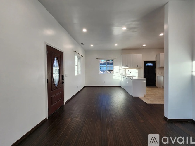 A spacious room with wooden floors and white walls.