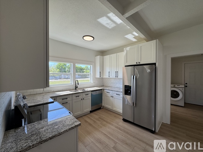 A kitchen with a refrigerator, sink, and cabinets.