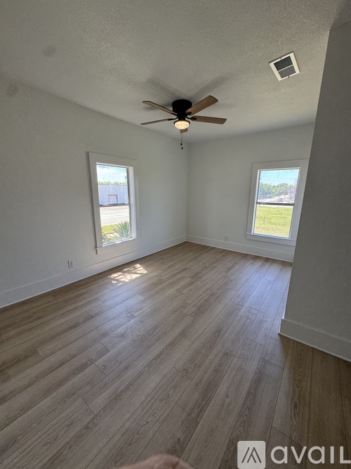 A room with a ceiling fan and two windows.