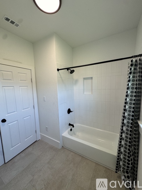 A bathroom with a white door and a white bathtub.