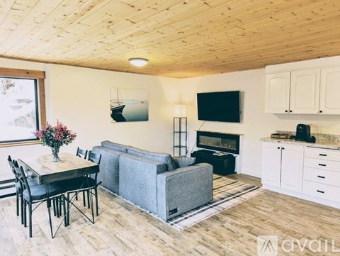 A living room with a grey couch, a black chair, a wooden table, and a television mounted on the wall.