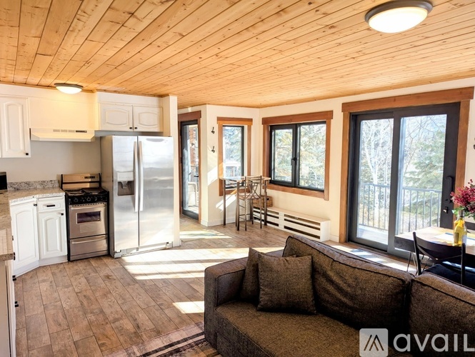 A living room with a couch and a kitchen area with a refrigerator and stove.