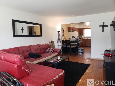 A living room with a red couch and a black and white mirror.