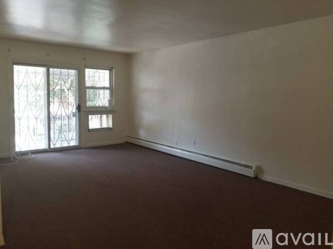 A room with a carpeted floor and a window with a view of trees.