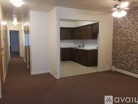 A room with a kitchenette and a ceiling fan.