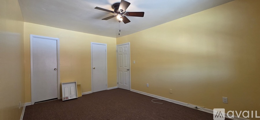 A carpeted room with a door and a wall.