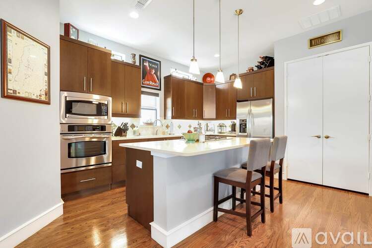 A kitchen with wooden cabinets and a white island with two chairs.