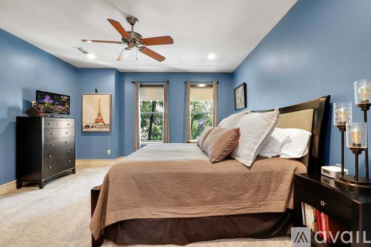 A bedroom with a large bed and a ceiling fan.